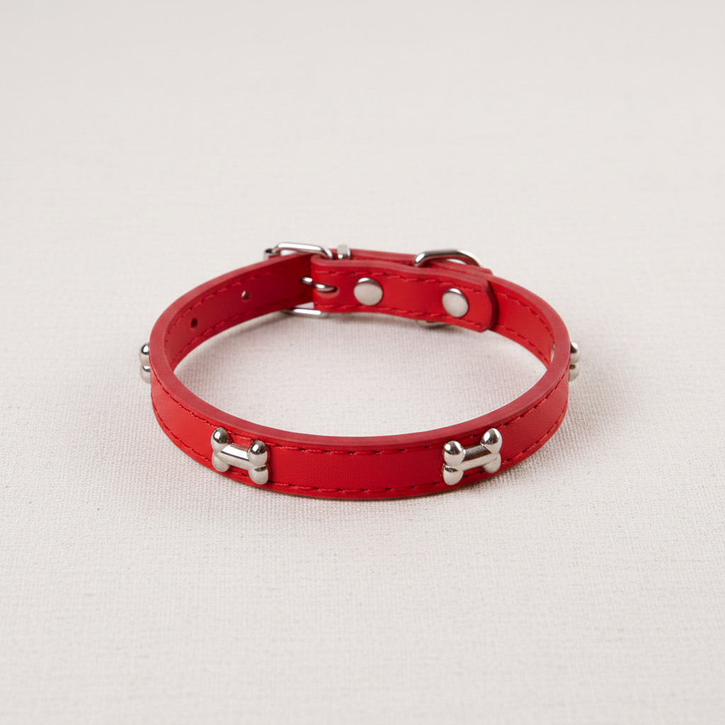 Red leather dog collar with bone studs on neutral background